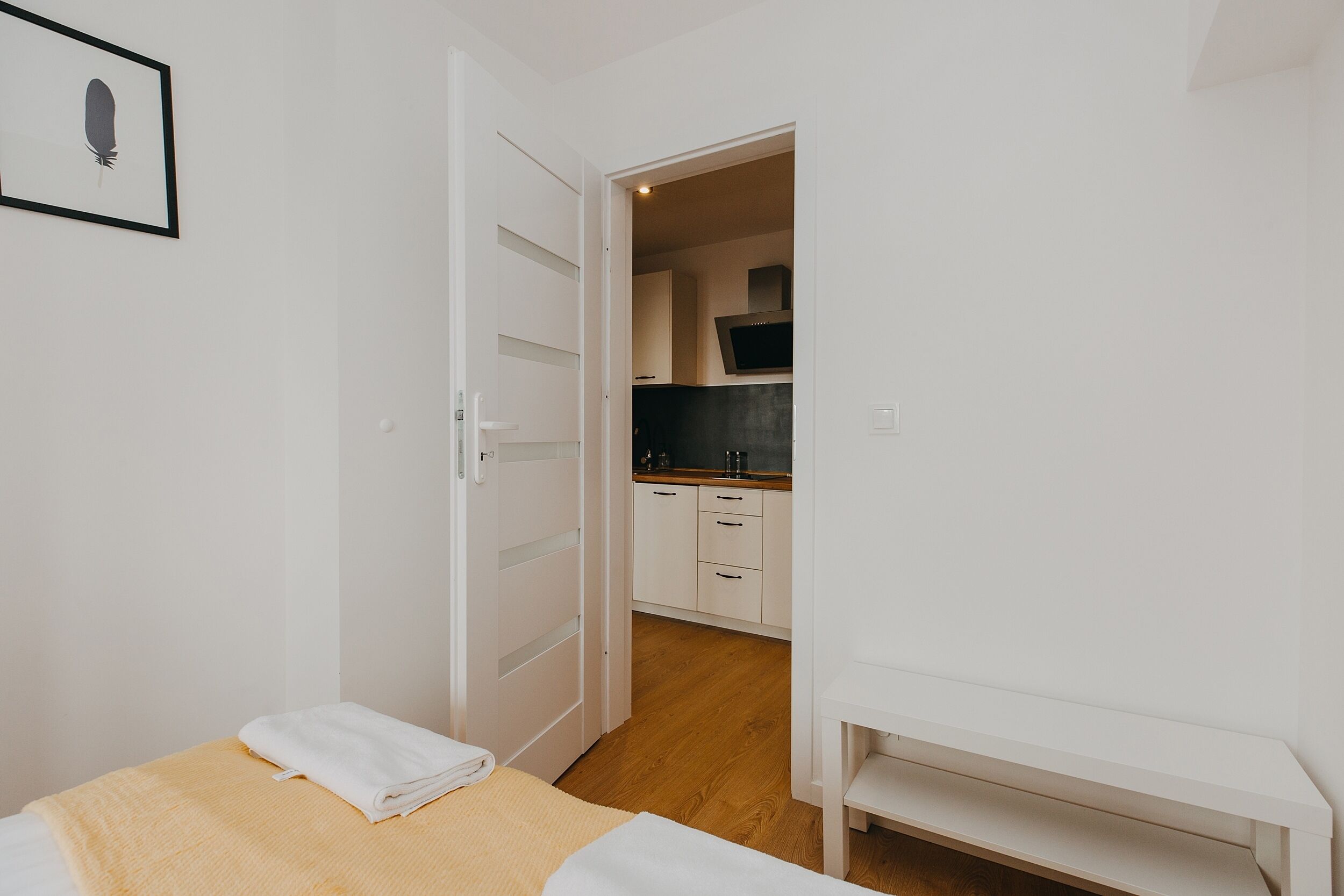 Ein Schlafzimmer mit einem Bett, einem Nachttisch und einer Tür zu einem Küchenbereich.