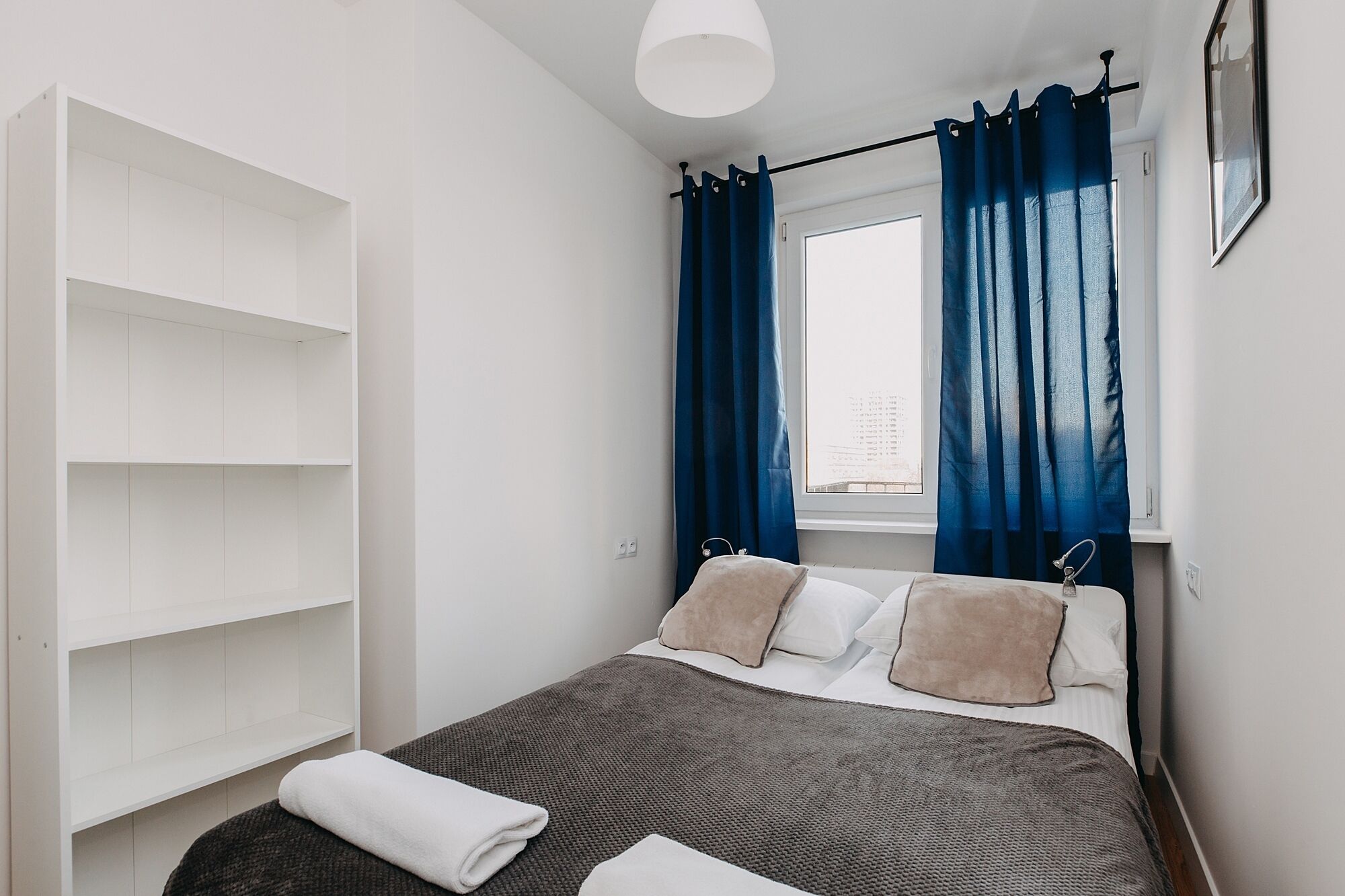A bedroom with a bed, a wardrobe, a window with curtains, and a towel on the floor.