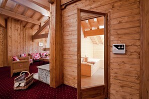 A wooden interior with a sauna, wooden benches, a stone bench, and a wooden door.