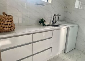 Eine moderne Küche mit weißen Schränken, einer Edelstahl-Spüle und einer weißen Toilette.