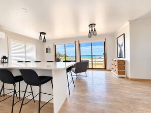 Eine moderne Küche mit einer großen Kochinsel, Barhocker und Blick auf den Strand.