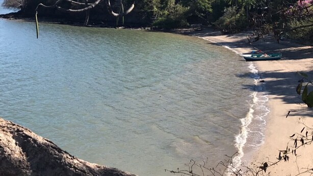 A beach with clear water, a sandy shore, and a boat. - Cabin (Provincia de Puntarenas)