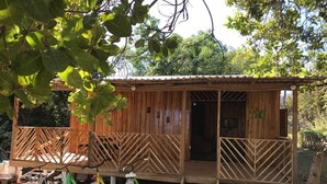 A wooden cabin with a porch, bicycles, and a ladder leading to the entrance. - Cabin (Provincia de Puntarenas)