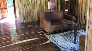 A wooden interior with a brown sofa and a glass coffee table. - Cabin (Provincia de Puntarenas)