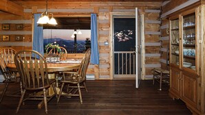 A wooden interior with a dining table, chairs, and a cabinet.