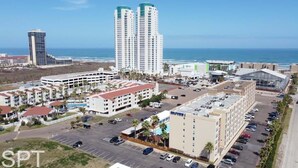 A hotel with multiple floors, a parking lot, and a view of the ocean.