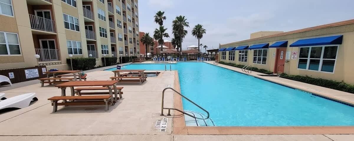 A swimming pool with lounge chairs and a lifeguard stand.