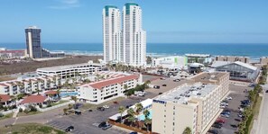 A hotel with multiple floors, a parking lot, and a view of the ocean. - Beach access Condo Nice pool/hot tub area w/bbq 2 Bedroom Home by RedAwning (South Padre Island)