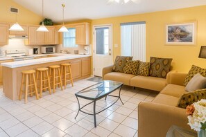 A modern kitchen with a central island, bar stools, and a dining area with a glass table.