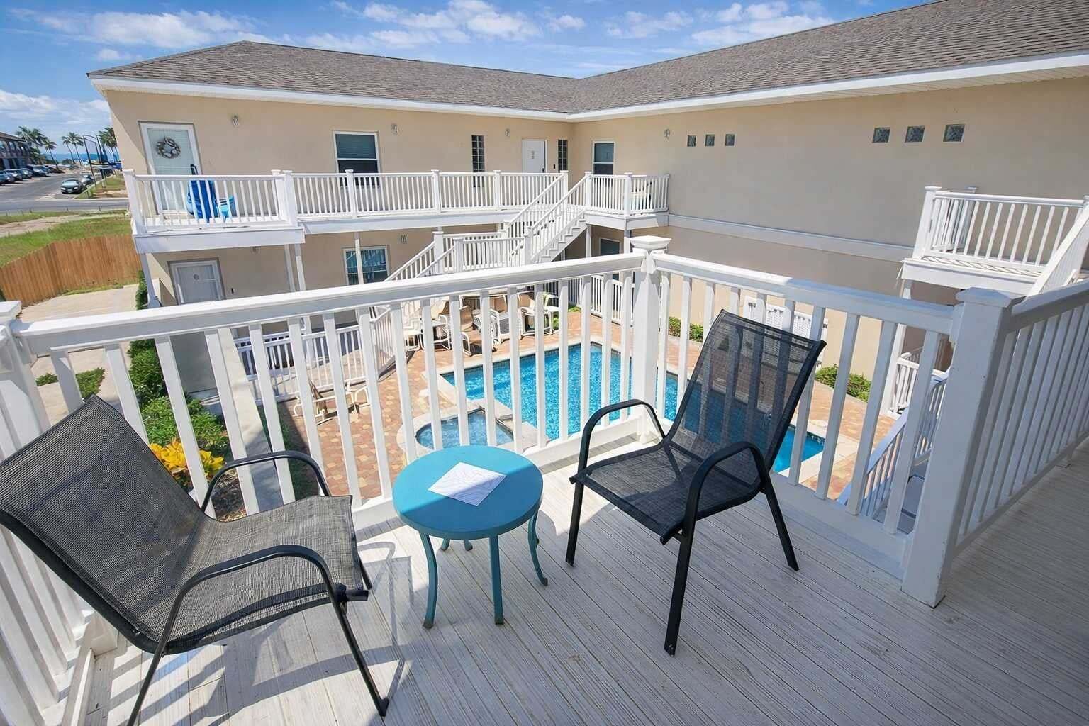 Ein Balkon mit Pool, weißen Geländern und zwei Stühlen.