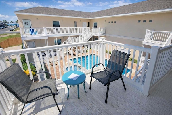 A balcony with a pool, white railings, and two chairs.