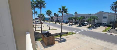 A residential street with palm trees, houses, and parked cars.