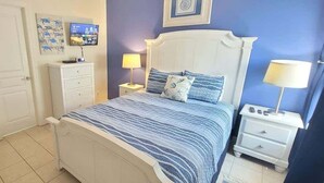 A bedroom with a bed, a nightstand, a dresser, and a television on the wall. - Los Cabos Iii #7 2 Bedroom Home by RedAwning (South Padre Island)