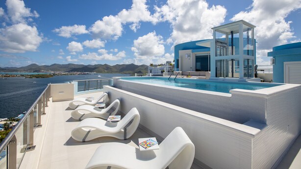 Un espace piscine aménagé sur le toit, avec des chaises longues et une structure entièrement vitrée.