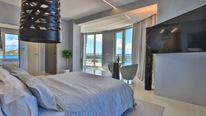 Une chambre moderne avec un grand lit, une télévision et une vue sur la mer.