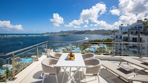 Un balcon avec une table et des chaises donnant sur une vue panoramique de la côte.