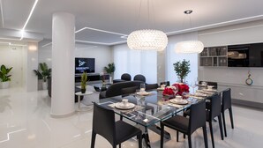 Un espace de salle à manger moderne avec une table en verre, des chaises noires et des luminaires élégants.