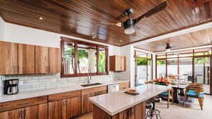 A modern kitchen with wooden cabinets, a large island, and a dining area with a table and chairs.