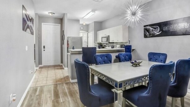 A modern dining area with a rectangular table and six blue upholstered chairs. - Luxury n cozy 3 bed 2 bath vacation property in a gated community (Kissimmee)