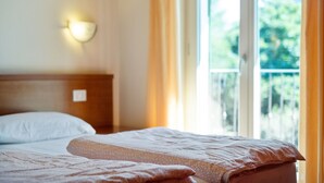 A hotel room with a bed, a nightstand, and a window with curtains. - Apartment by Lake Idro with Mountain Views (Idro (bs))
