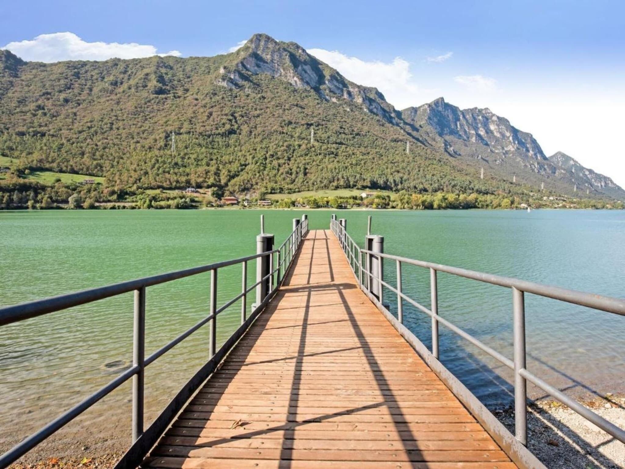 Een houten steiger die zich uitstrekt over een meer, met bergen op de achtergrond.