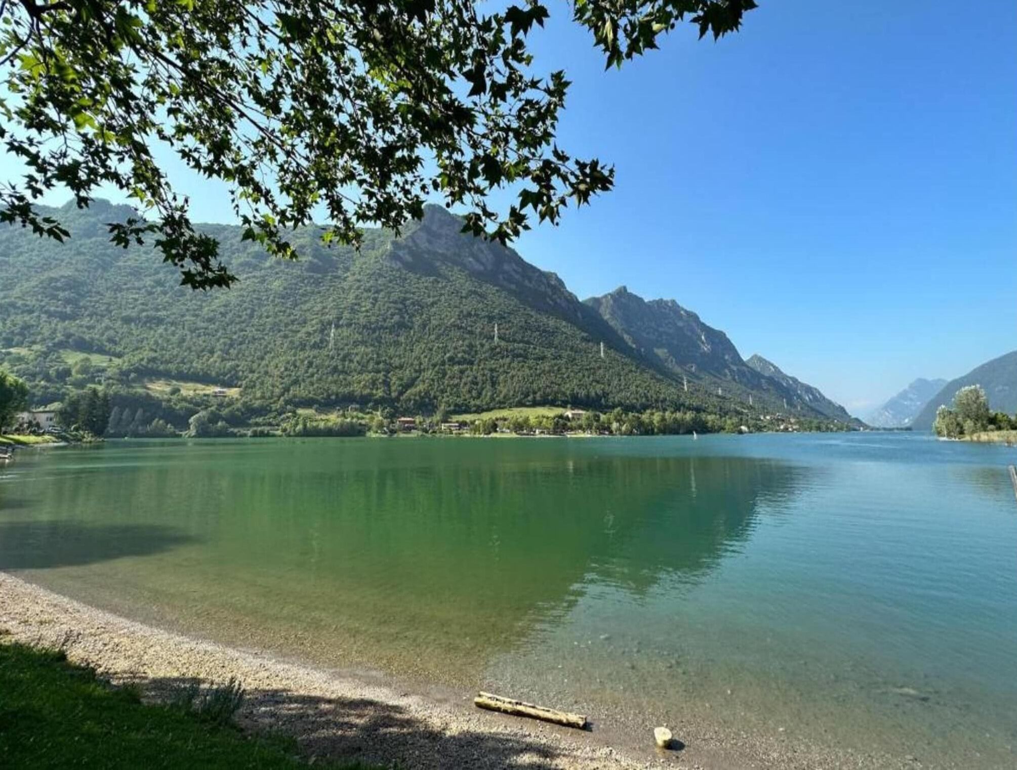 Un lago tranquilo con montañas al fondo y un cielo despejado.