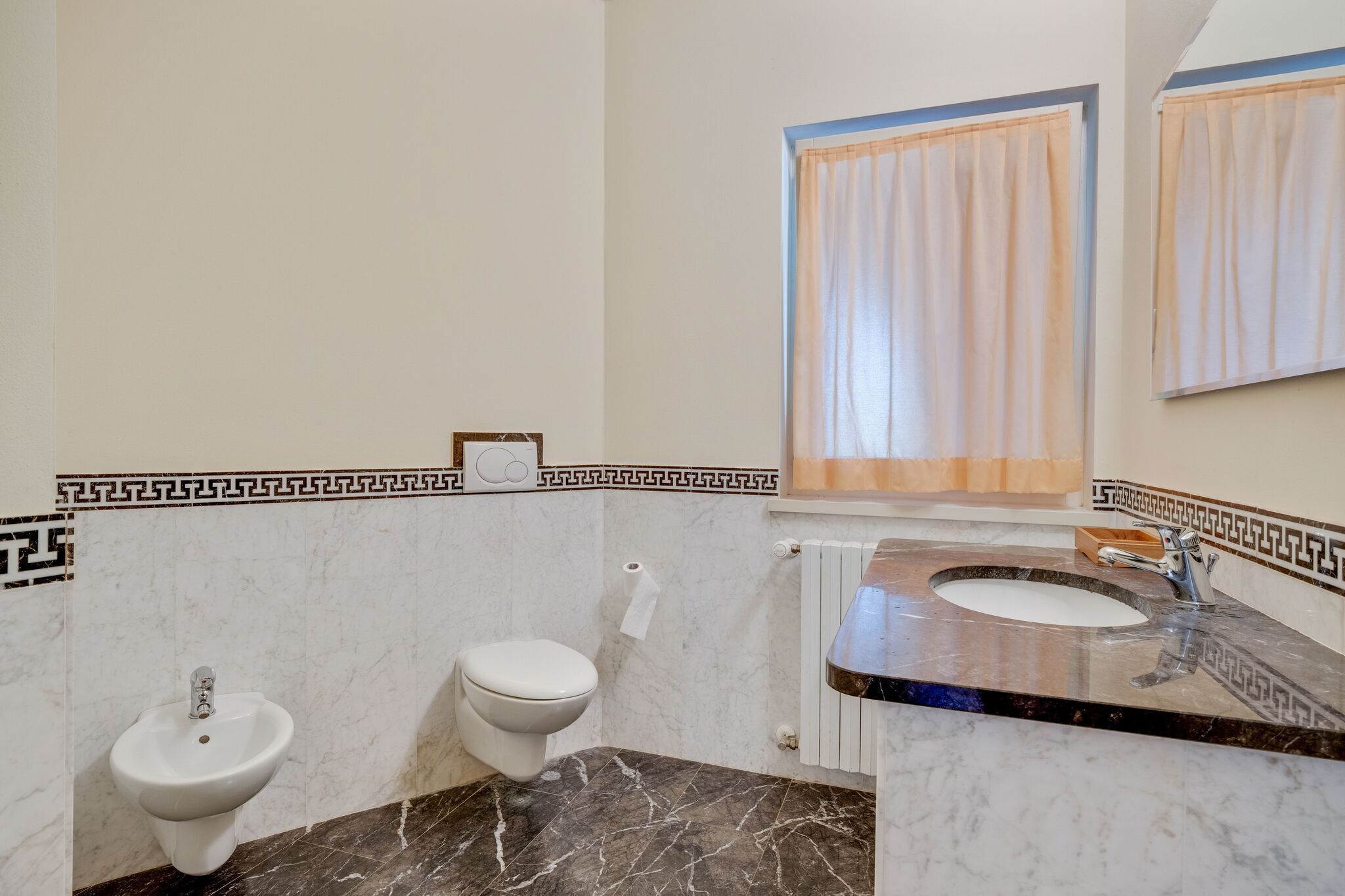 Un baño con un lavabo de mármol, un bidé, un inodoro y un perchero para toallas.
