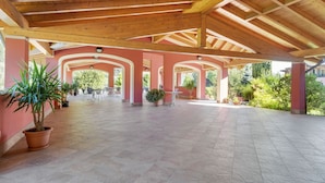 An open covered patio with tiled flooring, wooden beams, and potted plants. - Apartment on Lake Idro with Pool (Idro (bs))
