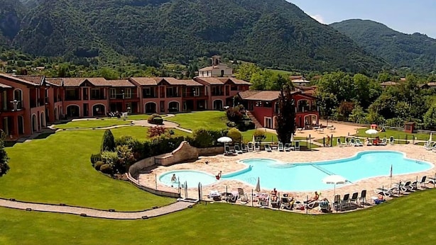 A resort with a large pool, multiple buildings, and a mountainous backdrop. - Apartment on Lake Idro with Pool (Idro (bs))