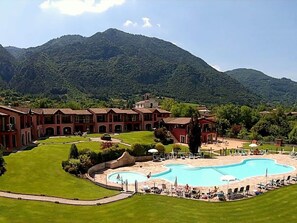 A resort with a large pool, multiple buildings, and a mountainous backdrop.