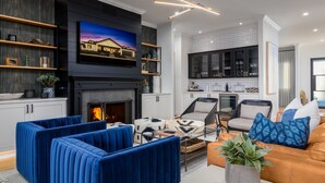 A modern living room with a fireplace, blue sofas, and a television mounted on the wall.