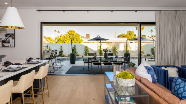 A modern living room with a sofa, coffee table, and dining area with chairs and a table.