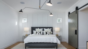 A bedroom with a bed, two bedside tables, a large window, and a sliding door.