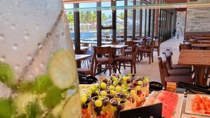 Un restaurante con vista a una piscina, mesas con comida y un cartel que dice "estacão Fit".