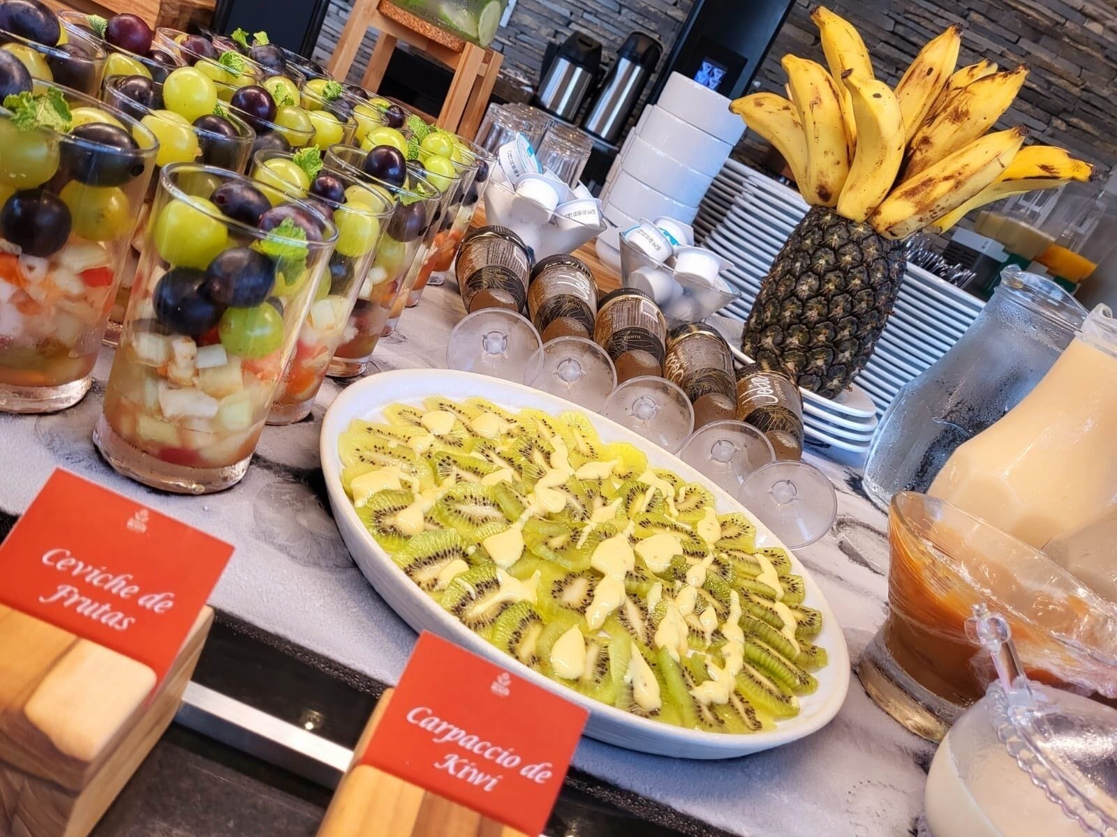 A fruit display with various fruits and a plate of sliced kiwi.