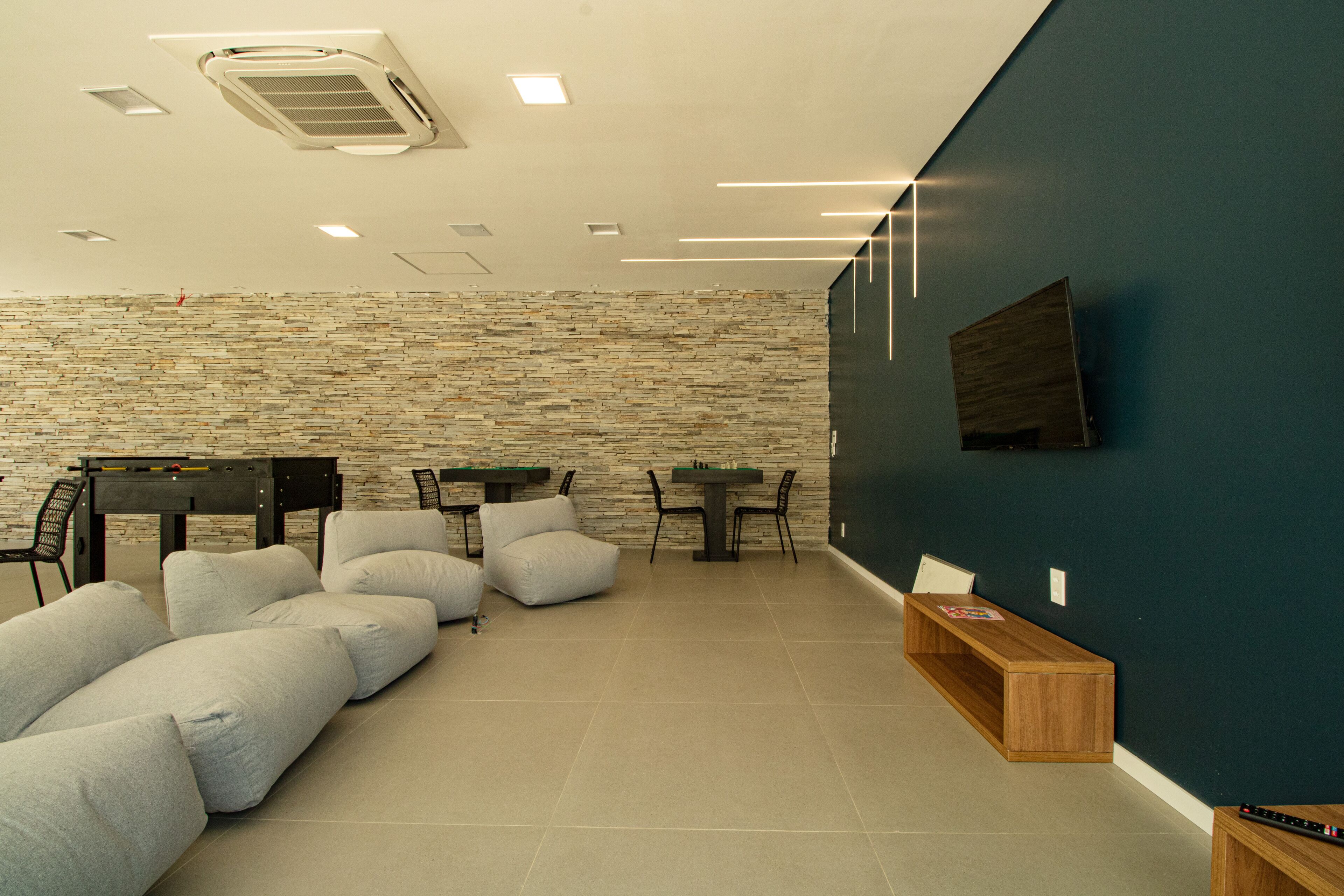 Una sala de estar moderna con pared de piedra, televisor de pantalla plana, mesa de billar y sofá.