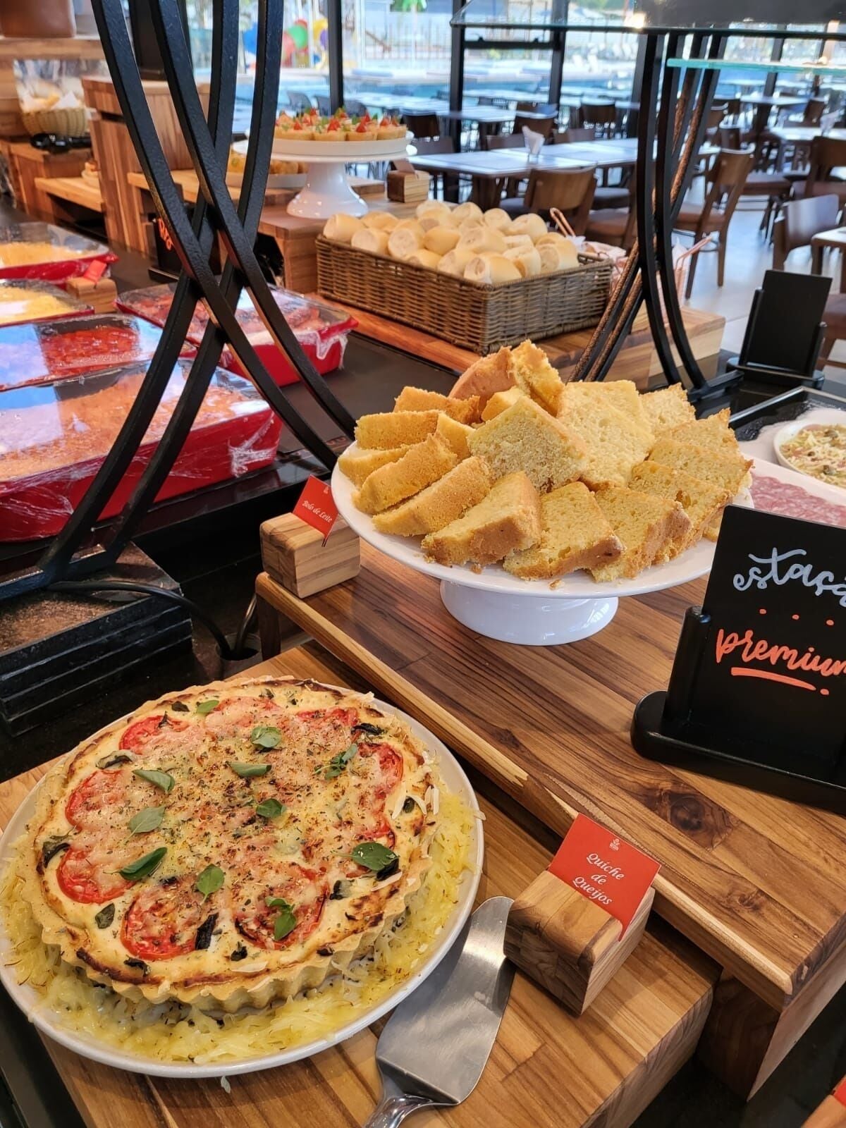Mostrador de restaurante con diversos alimentos, como pizza, pan y un cartel que indica una sección premium.
