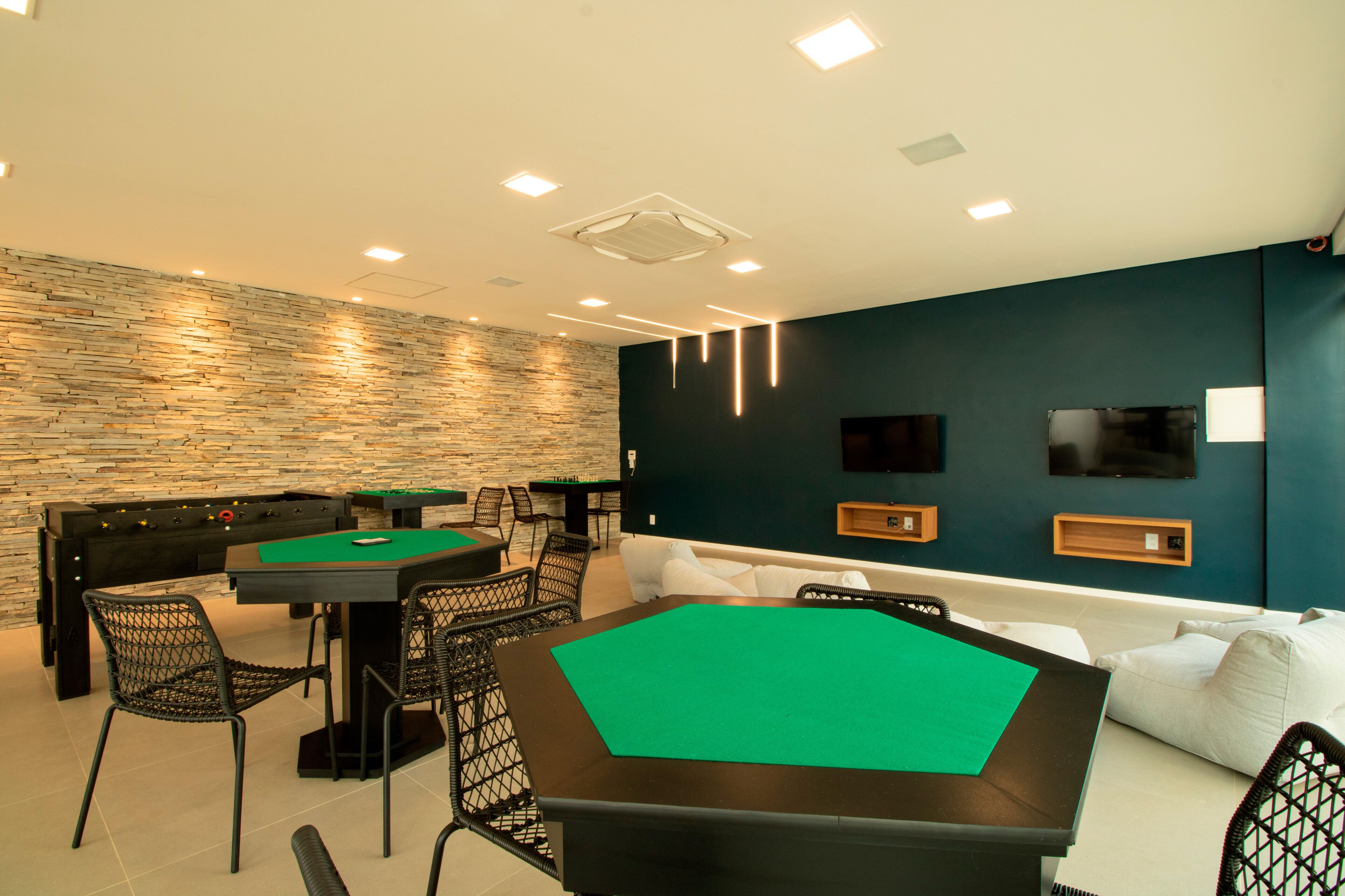 A modern indoor recreational area with a pool table, seating, and a foosball table.