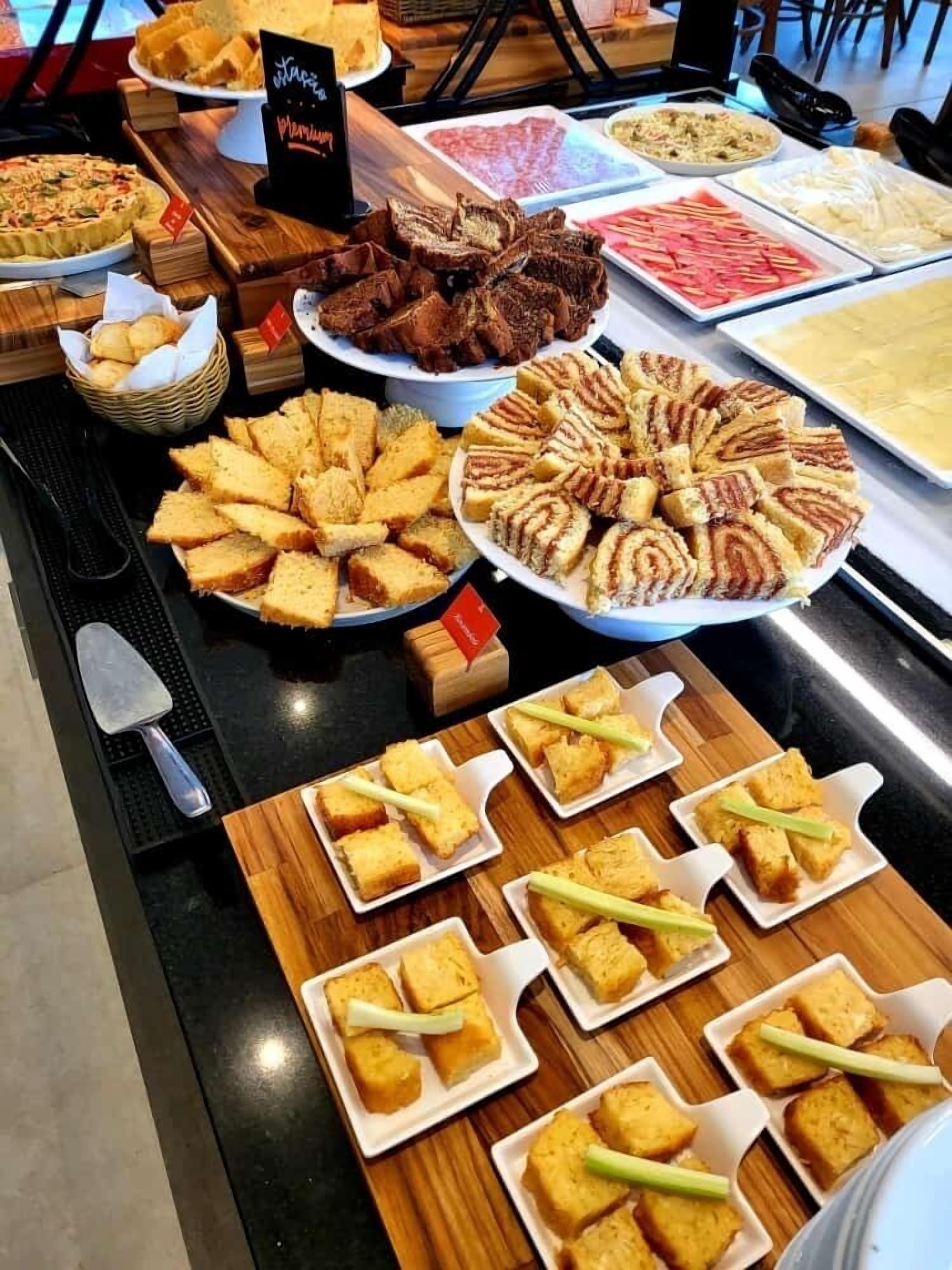 Un bufé con diferentes opciones de comida, incluyendo pan, pastelería y carnes.