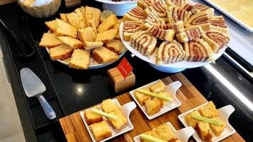 Un bufé con diferentes opciones de comida, incluyendo pan, pastelería y carnes.