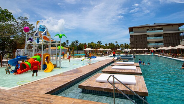 Un parque acuático con piscina, toboganes y zonas de descanso.