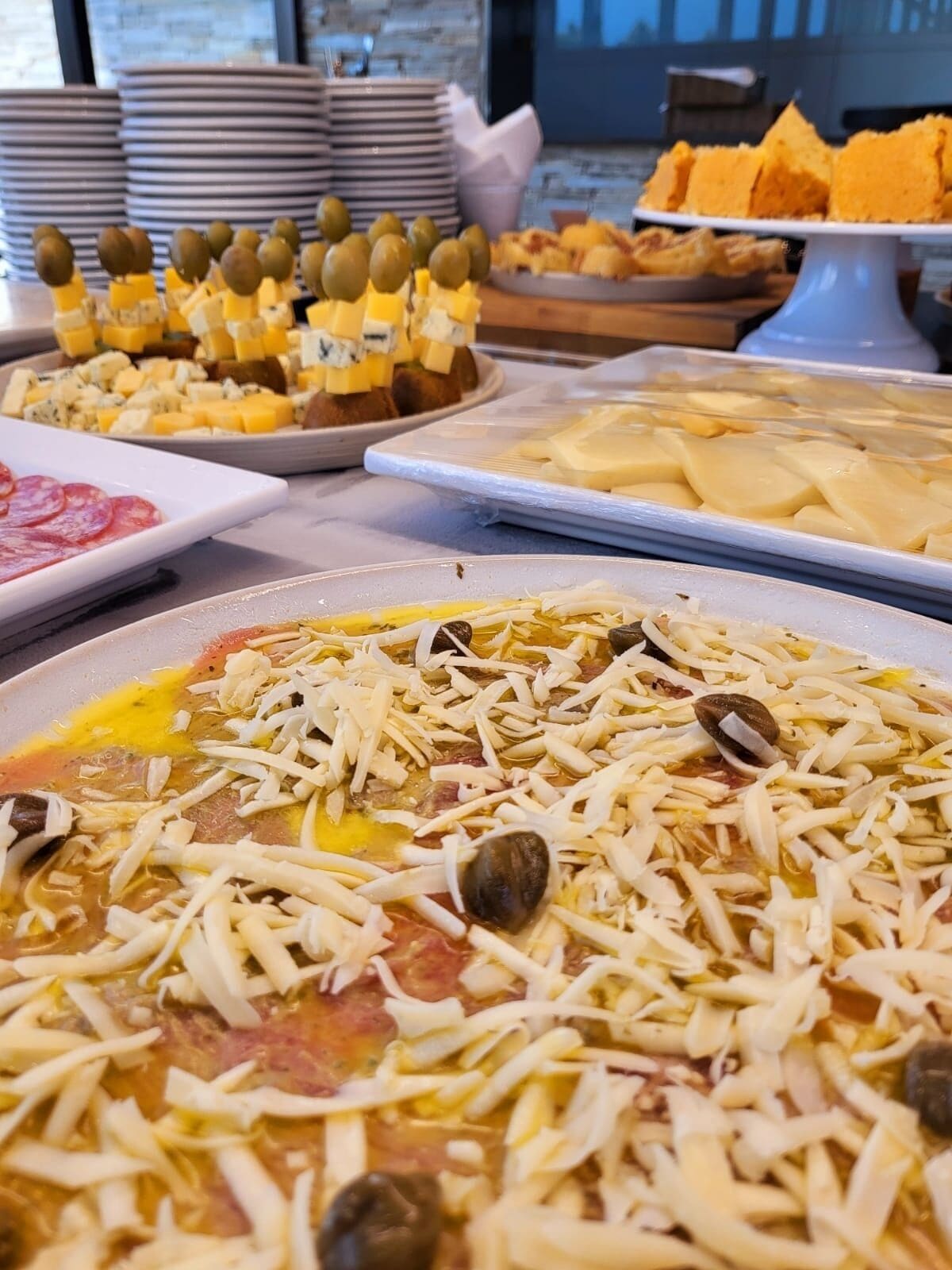 Un buffet con diversi piatti, tra cui pasta al formaggio e olive, e altri cibi.