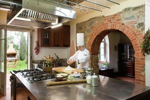 Uno chef prepara il cibo in una cucina con un'isola grande, un arco in mattoni e mobili in legno.