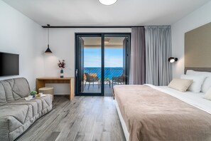 Une chambre d’hôtel moderne équipée d’un lit, d’un canapé, d’un bureau et d’un balcon avec vue sur la mer.