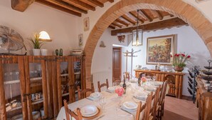 A dining room with a long table set for a meal, wooden cabinets with glass doors, and a rustic ceiling.