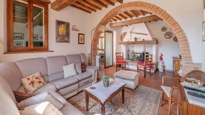A cozy living room with a sofa, coffee table, and chairs, a fireplace, and an arched brick structure.