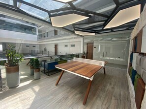Et moderne interiør med et træbord, potteplanter og gelænder af glas med udsigt over bybilledet.