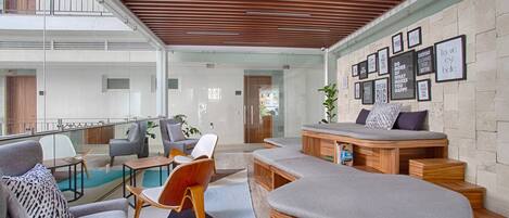 A modern living room with a glass wall, a pool, and a staircase leading to an upper level.