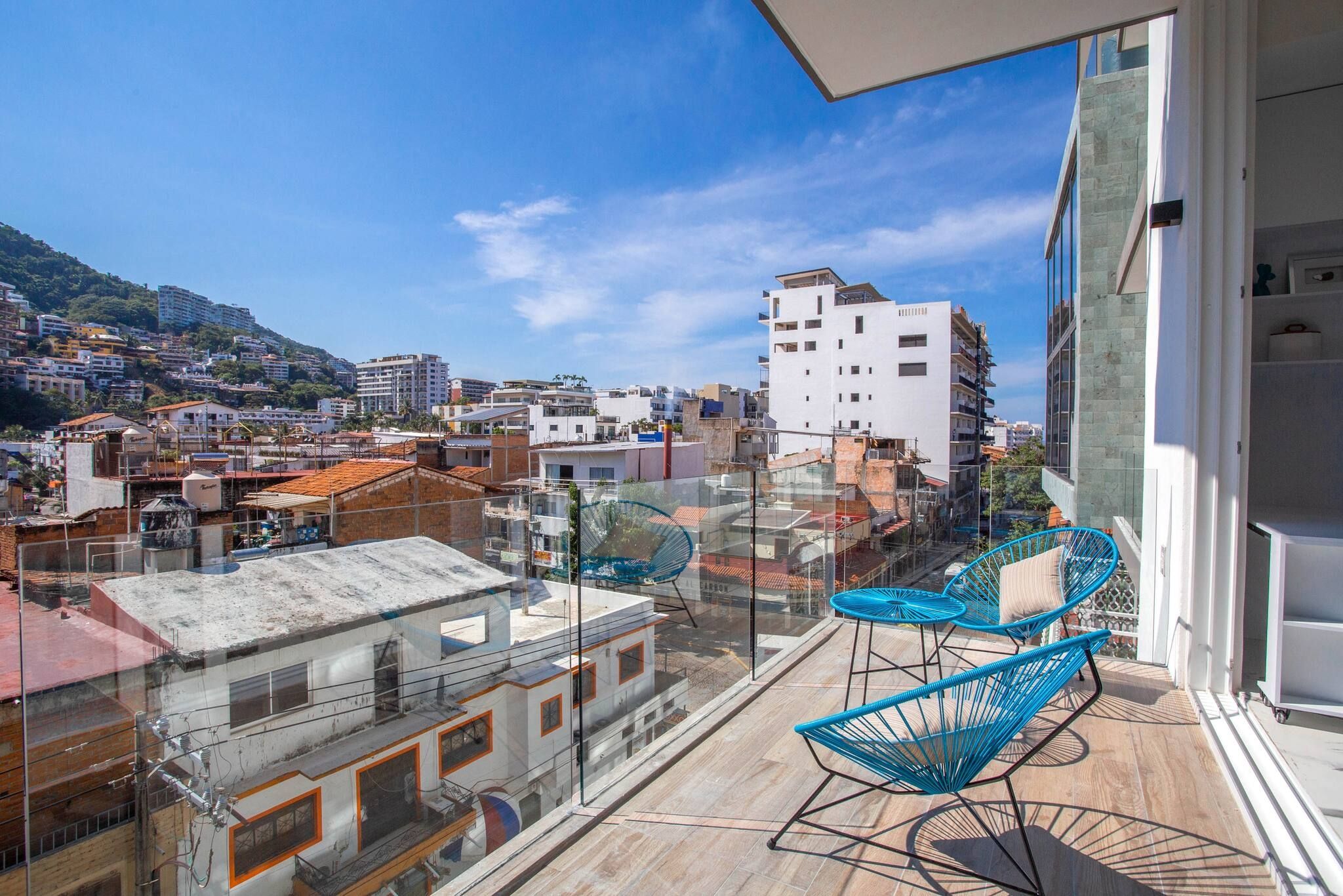 A balcony with a view of a cityscape, including buildings and a hill.
