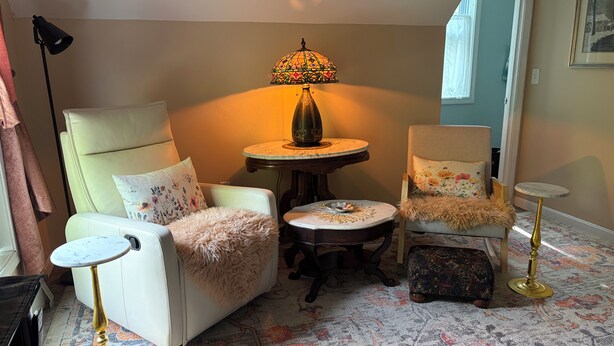 Una sala de estar acogedora con un sofá, un sillón y una mesita redonda con una lámpara.